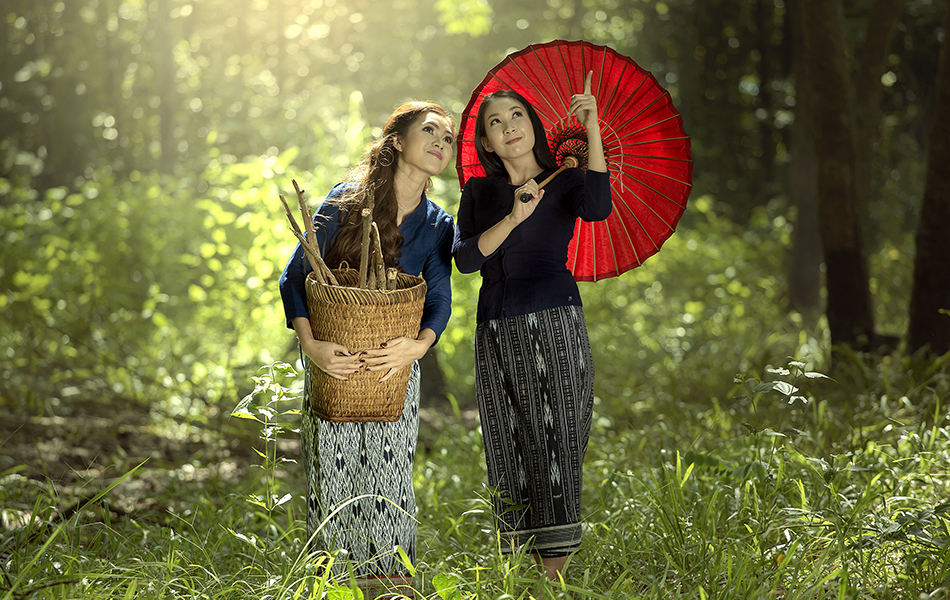Two Asian women in traditional thai dress walking the forest to collect the firewood